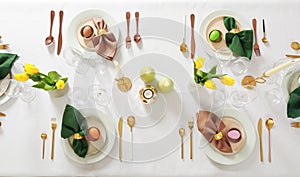 Festive Easter table setting with painted eggs, burning candles and yellow tulips, flat lay