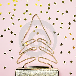 Festive evening golden clutch with star sprinkles on pink. Holiday and celebration background. Luxury accessories and party