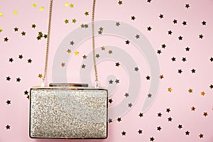 Festive evening golden clutch with star sprinkles on pink. Holiday and celebration background. Luxury accessories and party