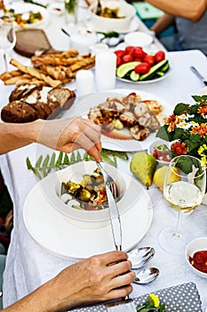 A festive family dinner or barbecue in the summer garden. Family leisure and celebration and food concept. People are eating