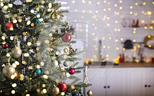 Festive fir tree branches with shiny red and golden baubles, balls, xmas ornaments and bright warm lights, garland. kitchen