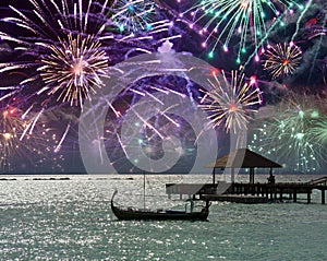 Festive fireworks over the sea and a boat silhouette on water. Maldives.