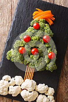Festive food: a healthy Christmas tree of fresh broccoli, cauliflower, tomatoes, pepper closeup. Vertical top view