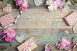 Festive frame of  pink peonies, gifts and hearts on an old turquoise background with shabby paint