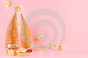 Festive gentle New Year background with glitter glossy gold decorations, Christmas tree, glowing stars lights on pink backdrop.