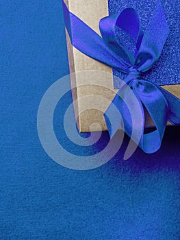 Festive gift wrapped present box with blue satin bow close up  on trendy blue background