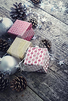 Festive Gifts with Boxes, Baubles, Pine Cones on Wooden Background.