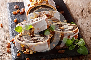 Festive glazed poppy beigli cake with raisins, walnuts close-up on a table. horizontal