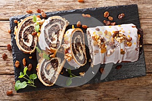 Festive glazed poppy beigli cake with raisins, walnuts close-up on a table. Horizontal top view