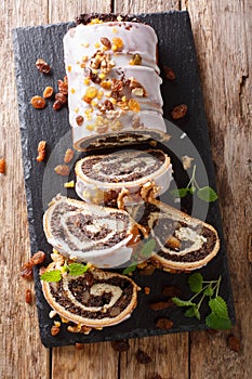 Festive glazed poppy beigli cake with raisins, walnuts close-up on a table. Vertical top view