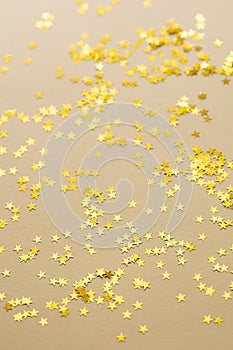 Festive golden stars of confetti are scattered on a light background