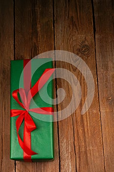 Festive green gift box with red satin bow, ribbon. A gift on a craft wooden background. Valentine's Day