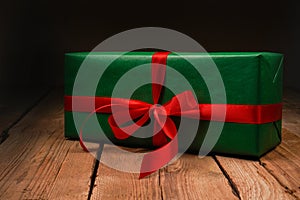 Festive green gift box with red satin bow, ribbon. Place for text, advertising. Holiday concept. A gift on a