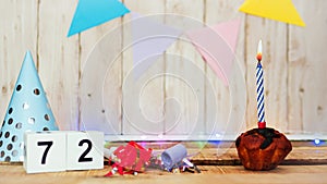 Festive Happy birthday background with number or digit 72. Postcard with a muffin and burning candles. Festive copy space