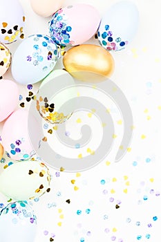 Festive Happy Easter background with decorated eggs, flowers, candy and ribbons in pastel colors on white. Copy space