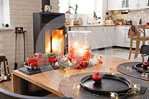 Festive interior of house is decorated for Christmas and New Year in loft style with black stove, fireplace, Christmas tree. Warm