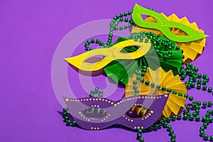 Festive Mardi Gras masquerade purple background. Fat Tuesday carnival, masks, beads, traditional decor