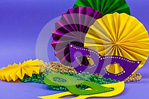 Festive Mardi Gras masquerade violet background. Fat Tuesday carnival, masks, beads, traditional decor