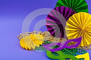 Festive Mardi Gras masquerade violet background. Fat Tuesday carnival, masks, beads, traditional decor