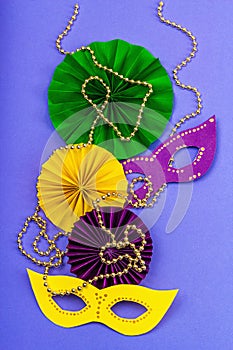 Festive Mardi Gras masquerade violet background. Fat Tuesday carnival, masks, beads, traditional decor