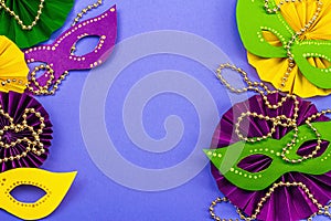 Festive Mardi Gras masquerade violet background. Fat Tuesday carnival, masks, beads, traditional decor