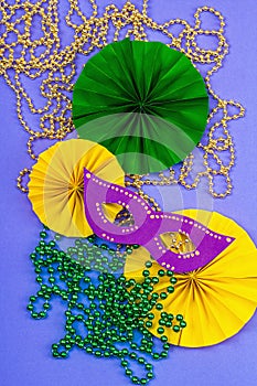 Festive Mardi Gras masquerade violet background. Fat Tuesday carnival, masks, beads, traditional decor