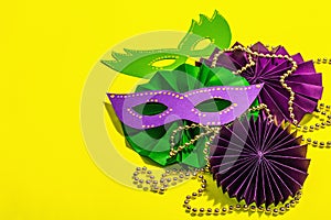 Festive Mardi Gras masquerade yellow background. Fat Tuesday carnival, masks, beads, traditional decor