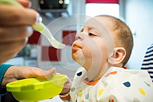 Festive meal. Mother feeding baby solid food for the first time