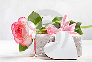 Festive mock up with gift box wrapped in floral paper, gentle pink rose, empty white wooden heart.