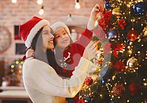 Festive mother and daughter decorating Christmas tree at home photo