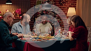 Festive multiethnic family enjoying Christmas dinner at home while eating traditional home cooked food