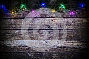 Festive New Year or Christmas background of dark old wooden boards, glowing garland of colored lights and Christmas balls