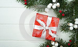 Festive New Year or Christmas composition with gift box and fir branches on the white wooden background. Close-up. Top view. Copy