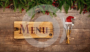 Festive New Year Christmas menu concept. Board with Menu text. Christmas decorations and Cutlery on wooden rustic table. Winter