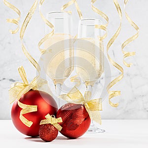 Festive New Year drink - sparkling champagne in glasses with shiny red decoration - balls, golden ribbon, curling confetti in soft
