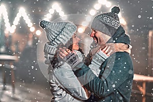 Festive New Year& x27;s mood, snow and romance. Loving couple warmly dressed on the background of a night street photo