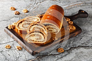 Festive nut roll made from yeast dough with walnuts and honey close-up on a wooden board. Horizontal