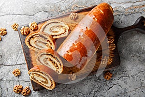 Festive nut roll made from yeast dough with walnuts and honey close-up on a wooden board. Horizontal top view