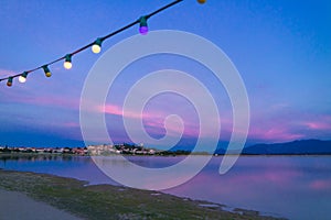 Festive outdoor electric light bulbs under blue sky at dusk