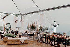 A festive outdoor event set up for a celebration, with a white tent, assorted tables and chairs
