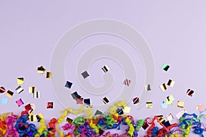 Festive party border or frame of colorful spiral streamers and confetti on pink background
