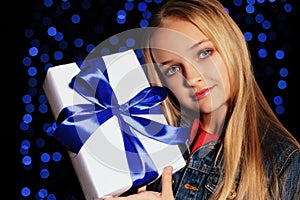 Festive photo of cute little girl whith long blond hair holding a gift-box