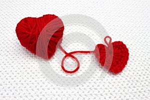 Festive photo, knitting with love. Handmade crochet heart and red yarn ball like a heart on the white crochet background. Red hear