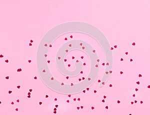 Festive pink background with spangles in the shape of heart.