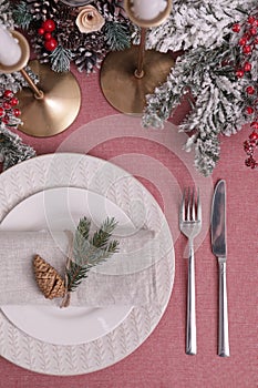 Festive place setting with beautiful dishware, cutlery and cone for Christmas dinner on pink tablecloth, flat lay