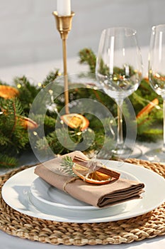 Festive place setting with beautiful dishware, fabric napkin and dried orange slice for Christmas dinner on white table