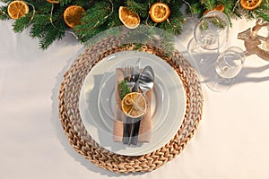 Festive place setting with beautiful dishware, fabric napkin and dried orange slice for Christmas dinner on white table, flat lay