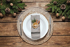 Festive place setting with beautiful dishware, fabric napkin and dried orange slice for Christmas dinner on wooden table, flat lay