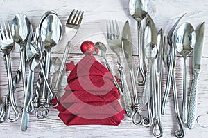 Festive place setting for christmas holiday dinner. Various of cutlery and red napkin shape christmas tree