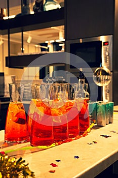 Festive Purim table with vibrant orange drinks in pitchers and glasses, adorned with holiday tinsel and confetti